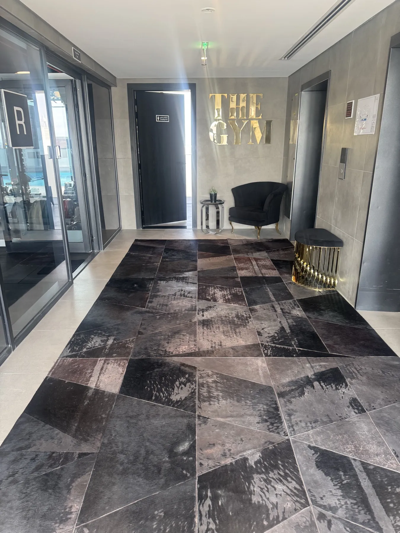 Entrance lobby of The Gym with the gold logo on the wall and stone floor